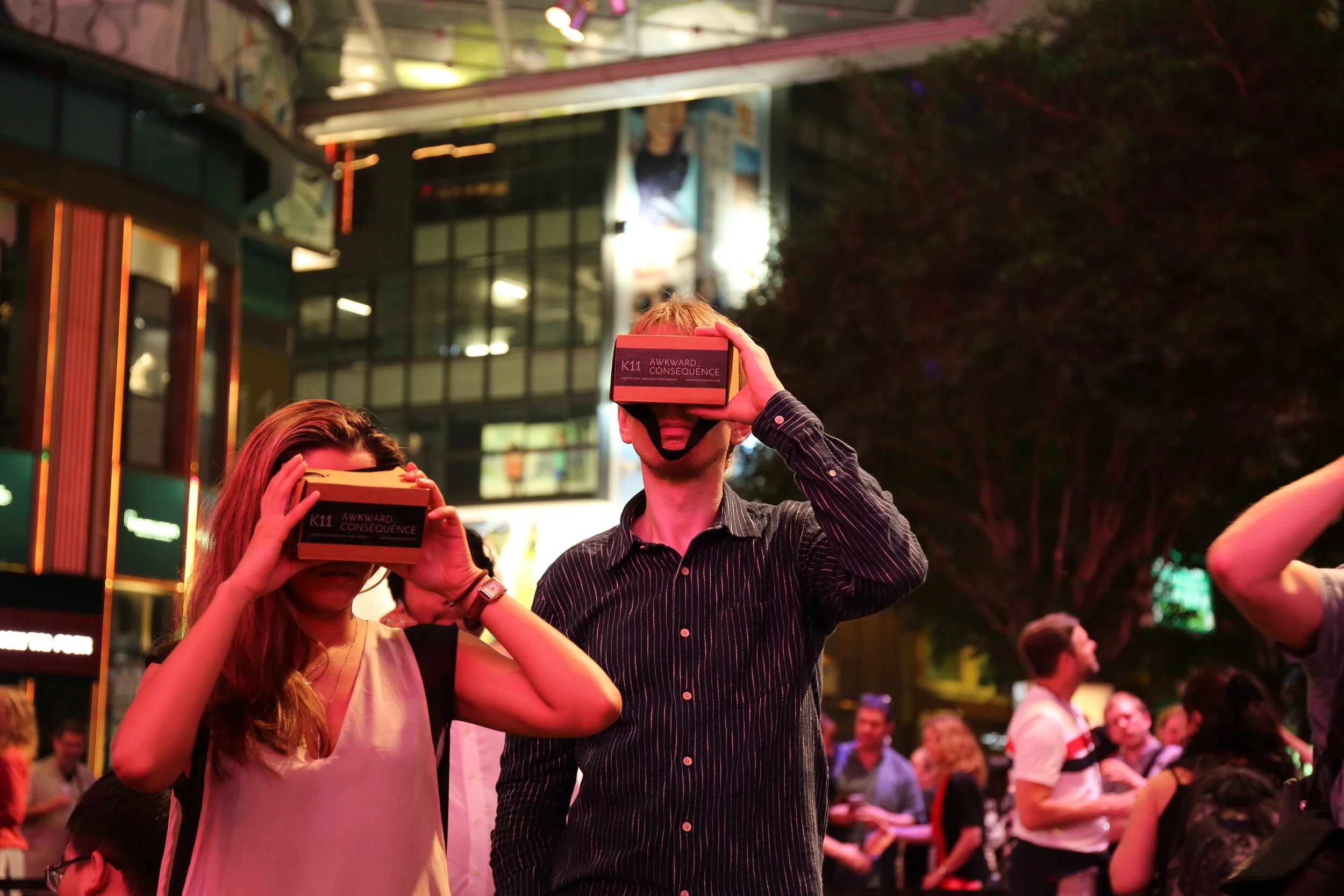 Two participants hold red VR viewers to their eyes.