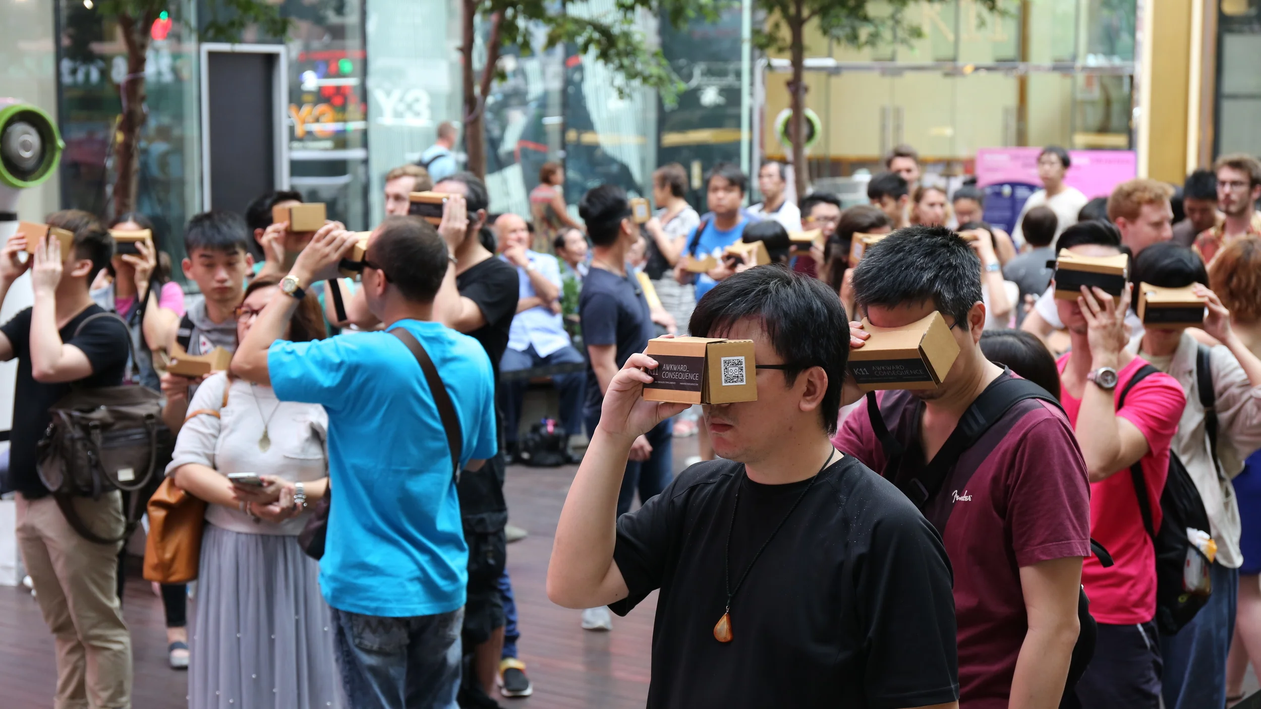 Audience members use handheld cardboard VR viewers during the outdoor performance.