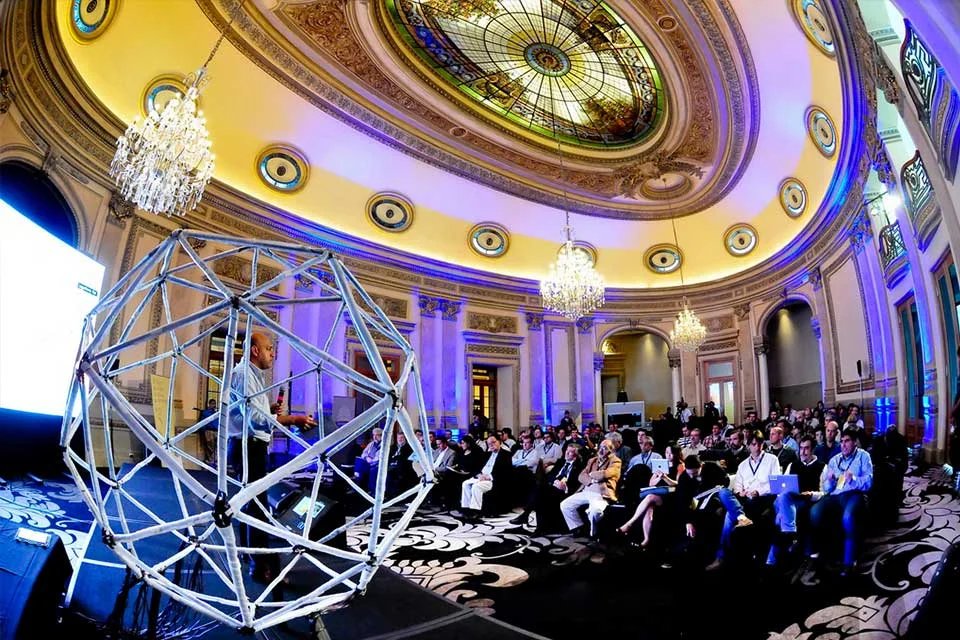 Barcelona’s illuminated geometric structure stands before an audience in an ornate hall.