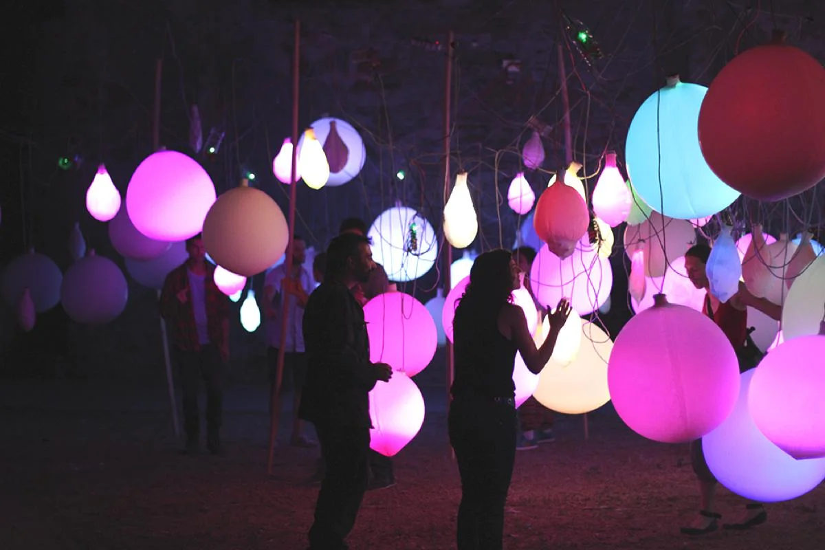 Visitors walking among hanging illuminated balloons at Celebra.