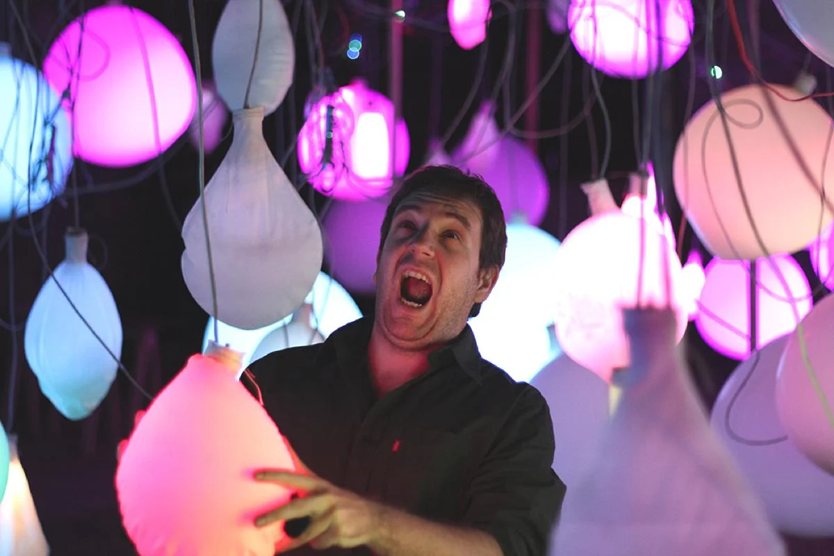 A participant with an open mouth holding a brightly lit balloon.