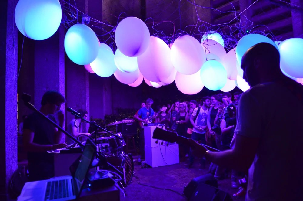 Musicians performing beneath glowing white, cyan and purple balloons at Celebra.