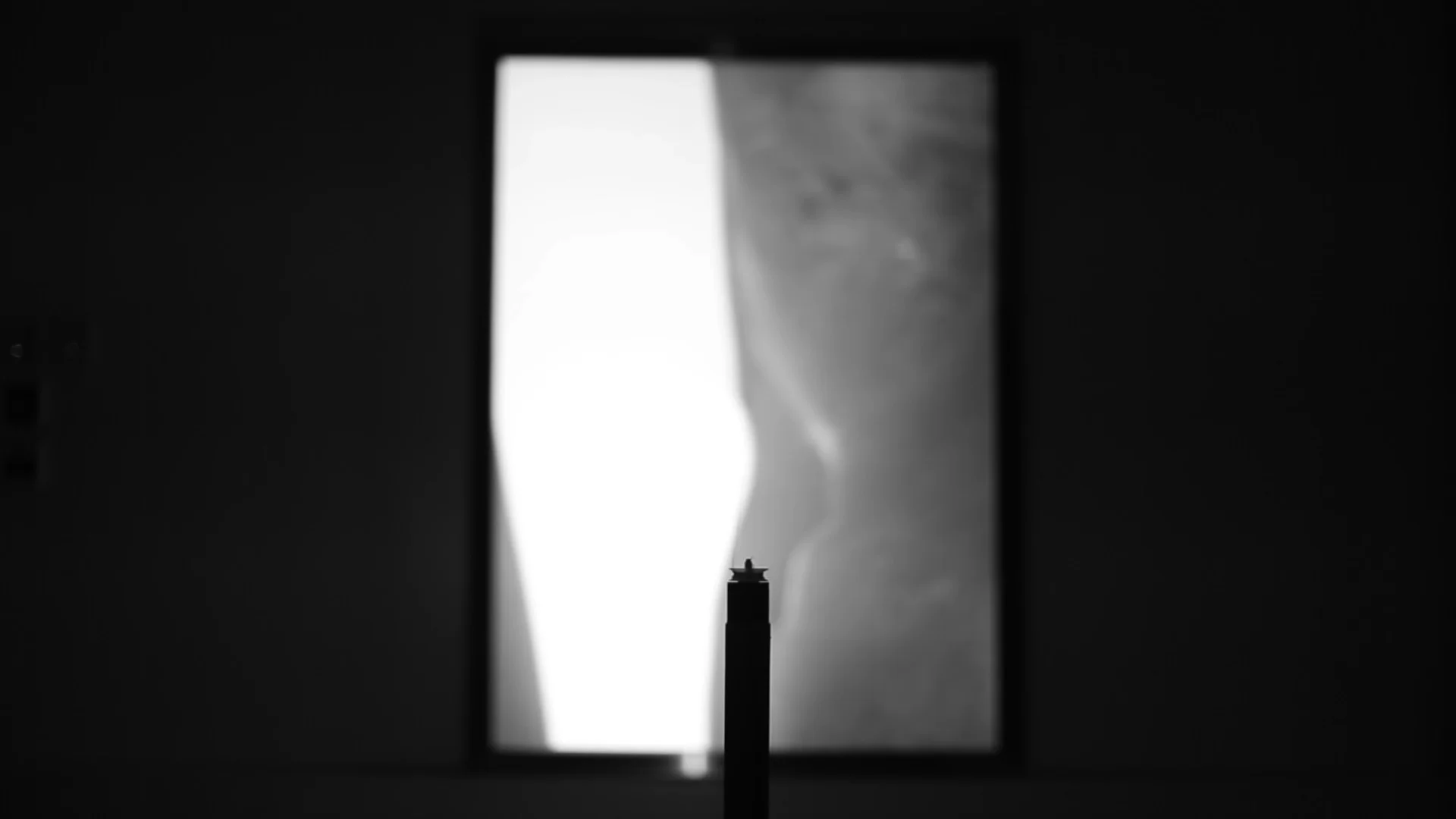 A monochrome projection on the framed screen in a dark gallery.