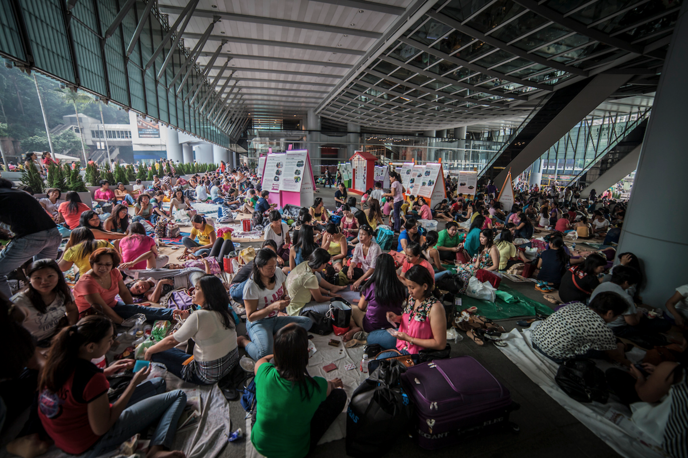 A group seated beneath a covered walkway with food and containers.