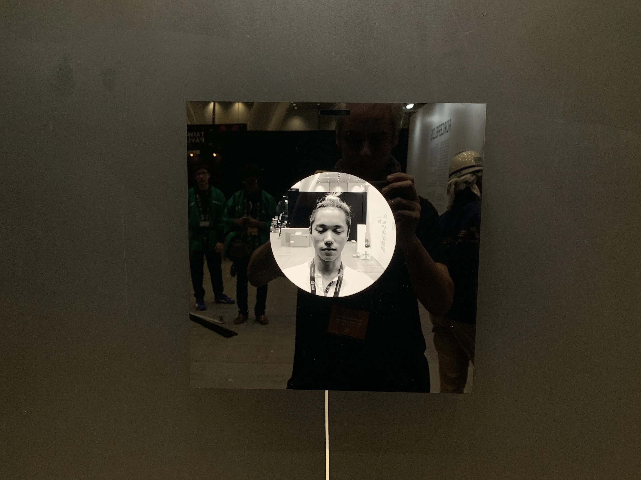 A circular black-and-white portrait on the reflective square display.