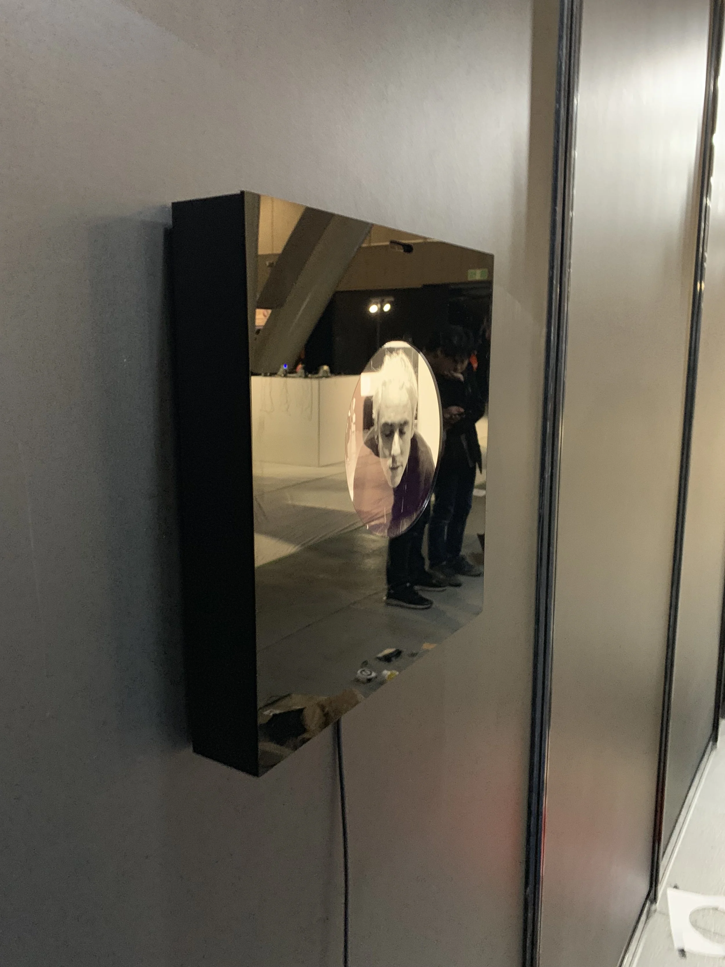 Side view of the wall-mounted reflective display and its portrait.
