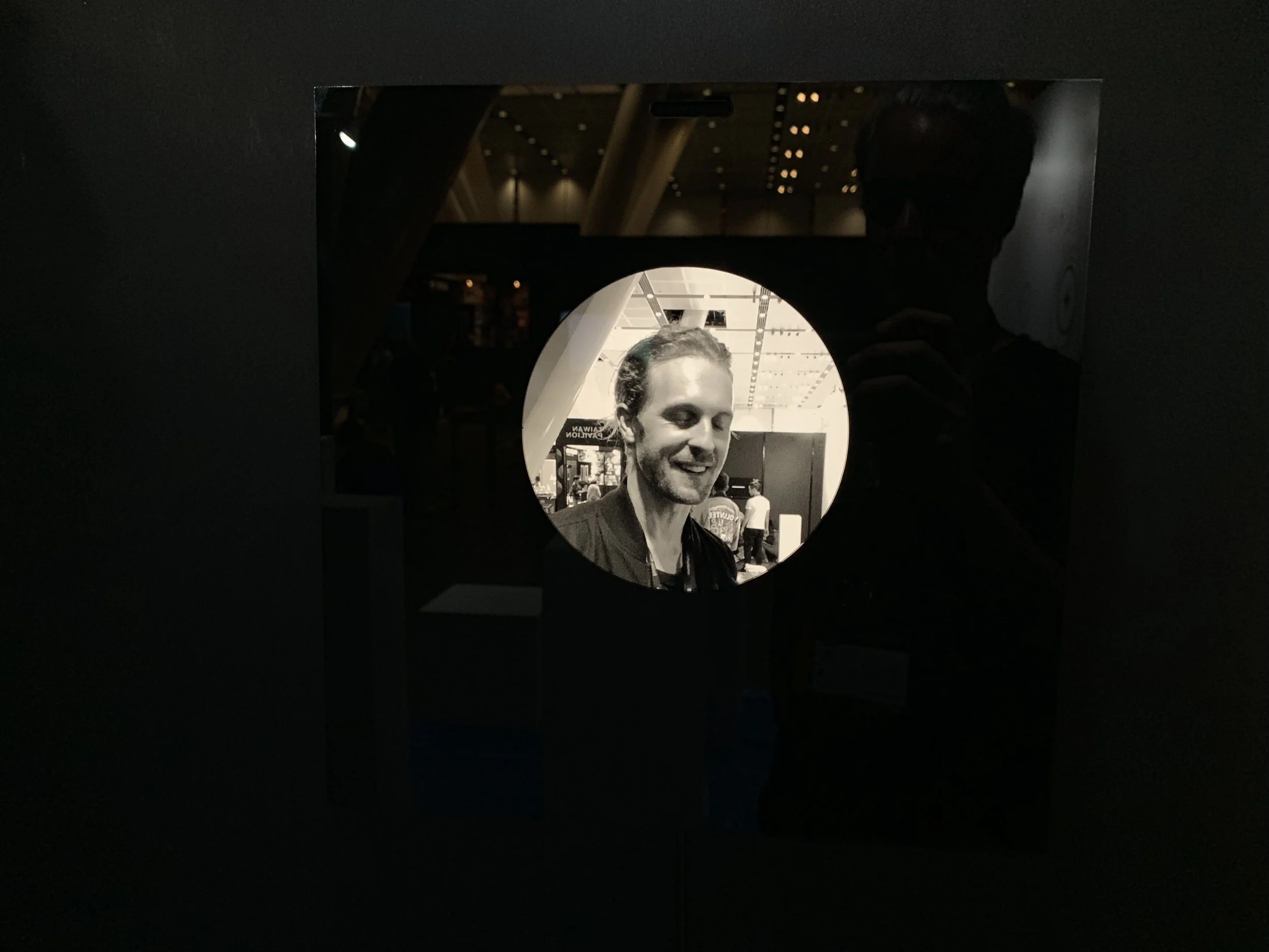 A smiling closed-eye portrait within the installation’s circular display.