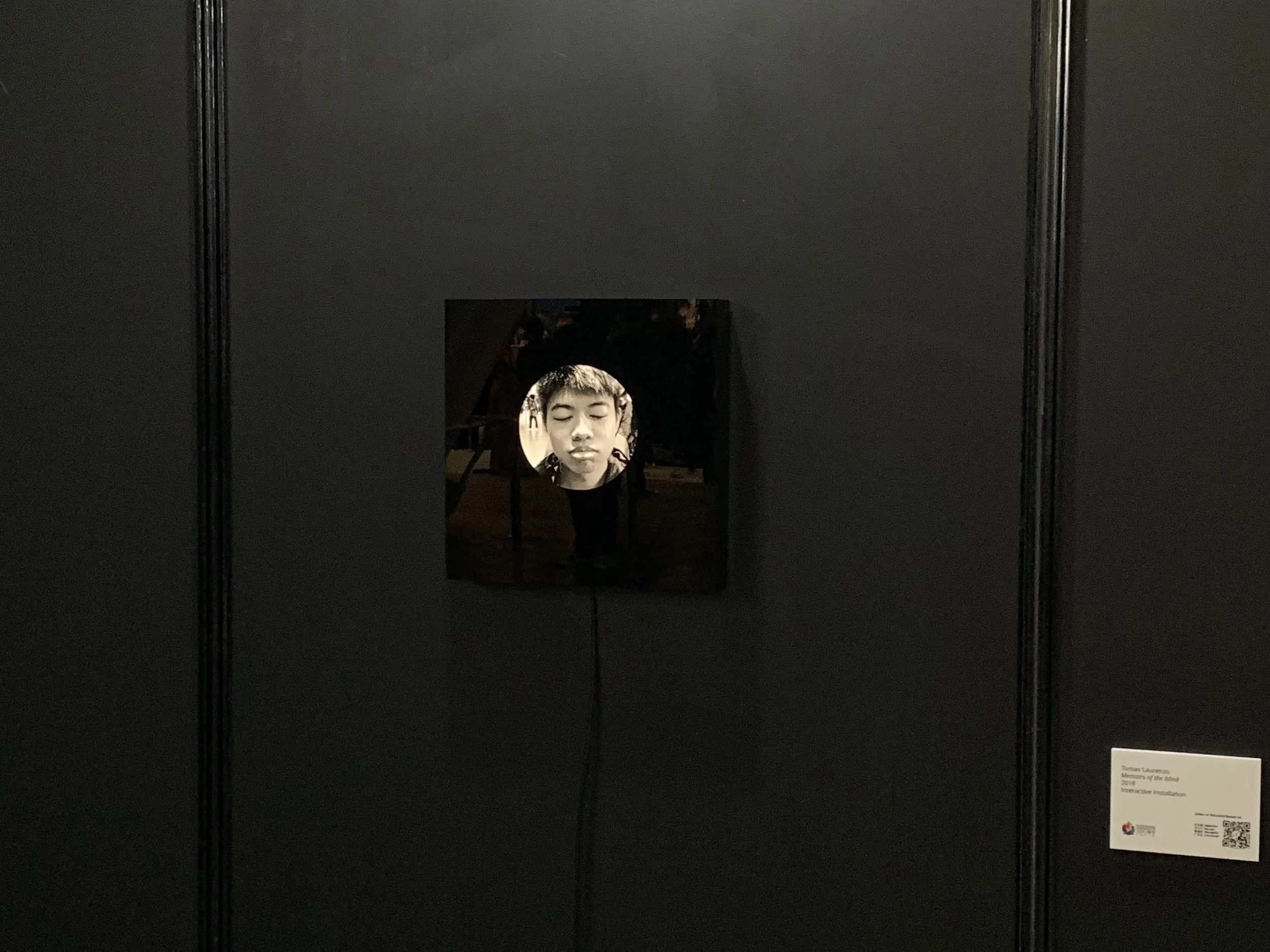 The portrait display and exhibition label on a dark gallery wall.