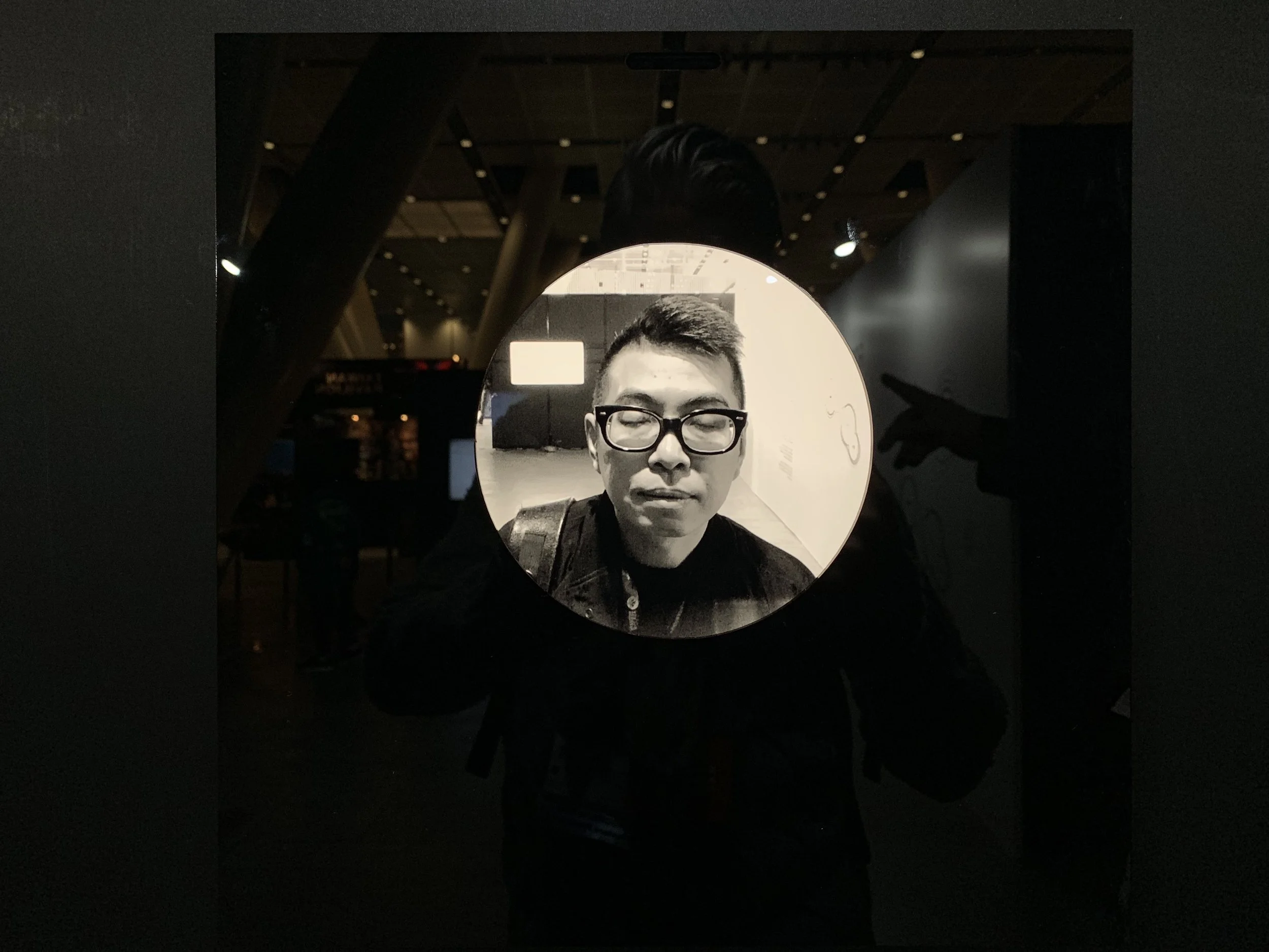 A closed-eye portrait wearing dark glasses appears on the reflective display.