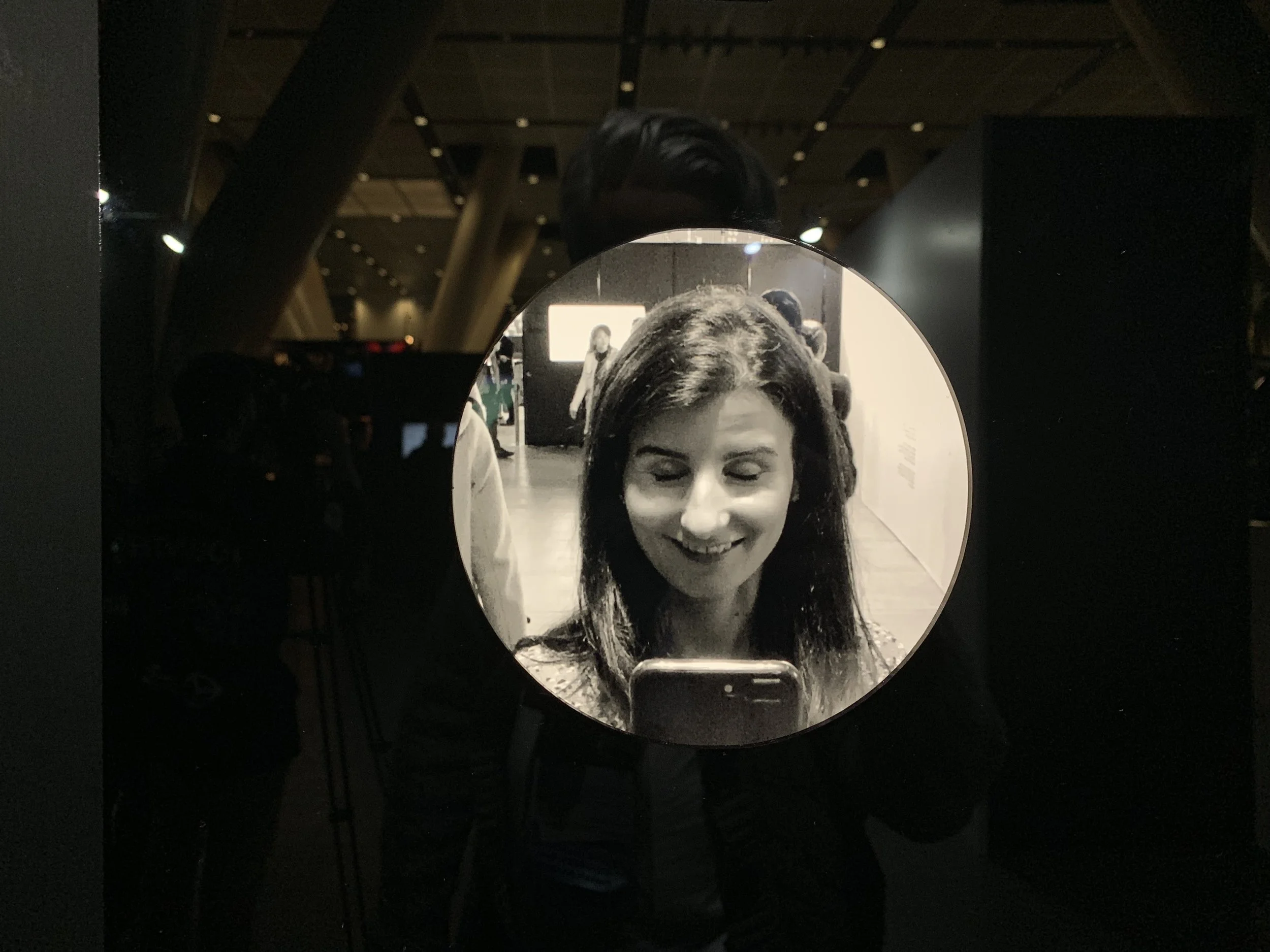 A smiling portrait in the circle, surrounded by reflections in the display.