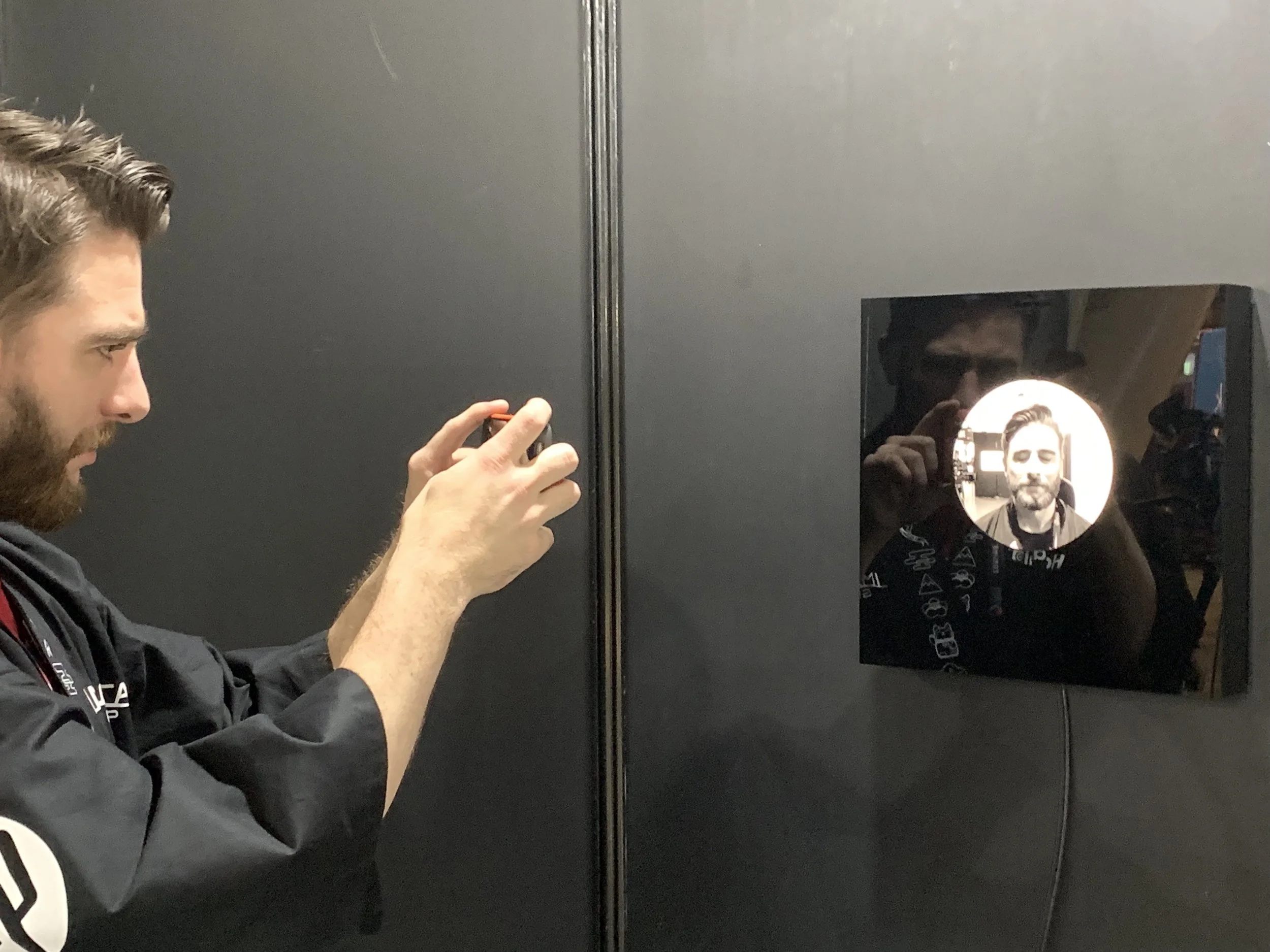 A visitor photographs the wall-mounted portrait display.