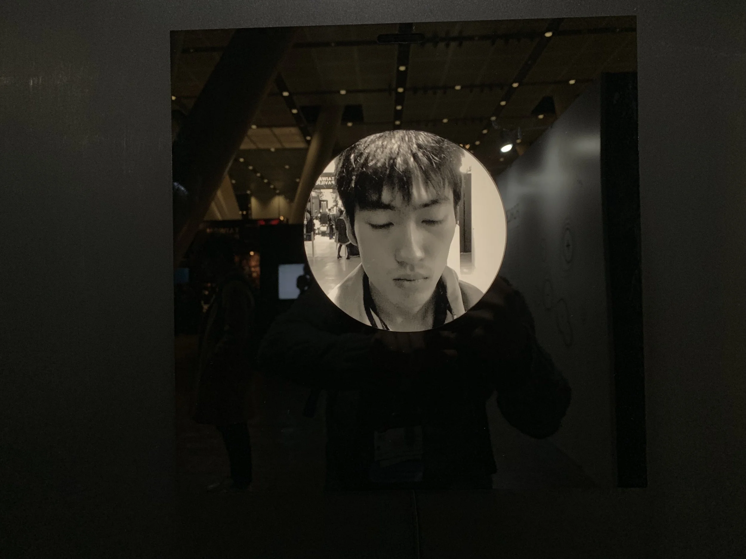 A closed-eye portrait against reflections in the glossy black display.