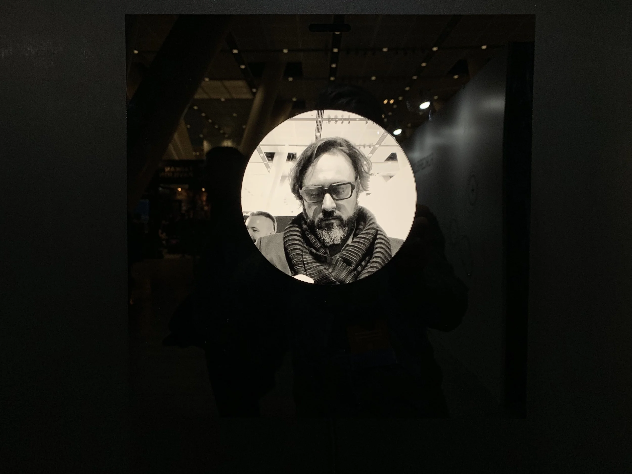 A bearded closed-eye portrait within the black square display.