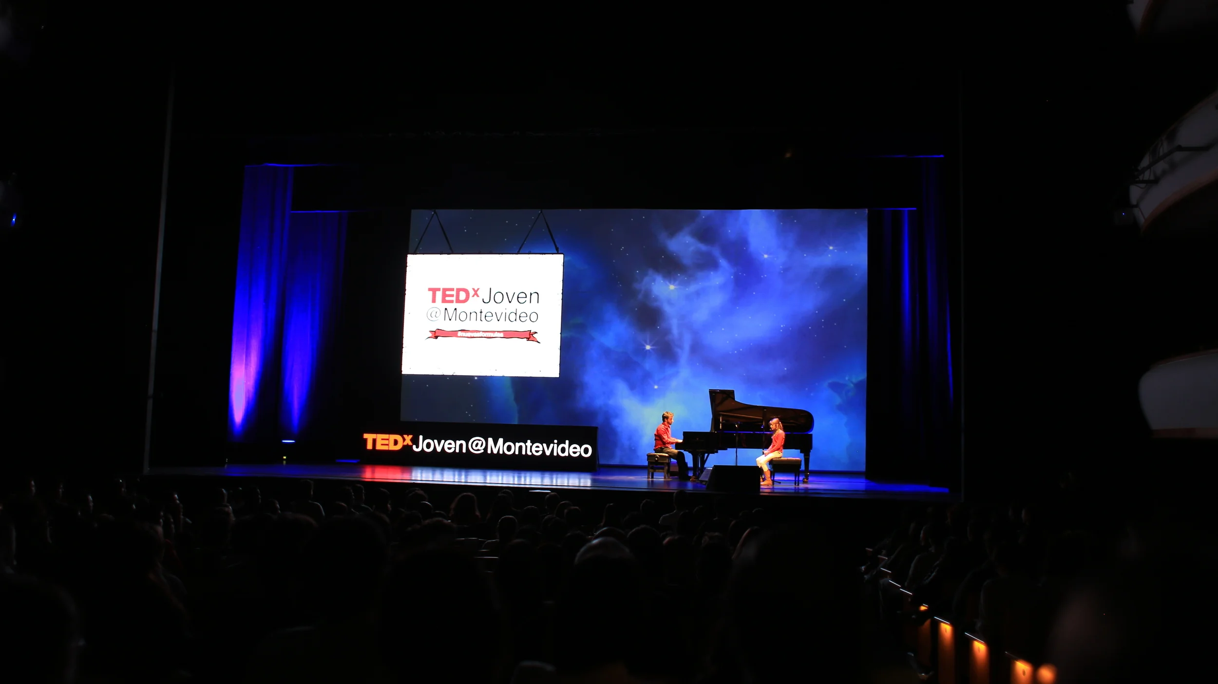 A pianist performs before projected blue imagery at TEDx Montevideo.