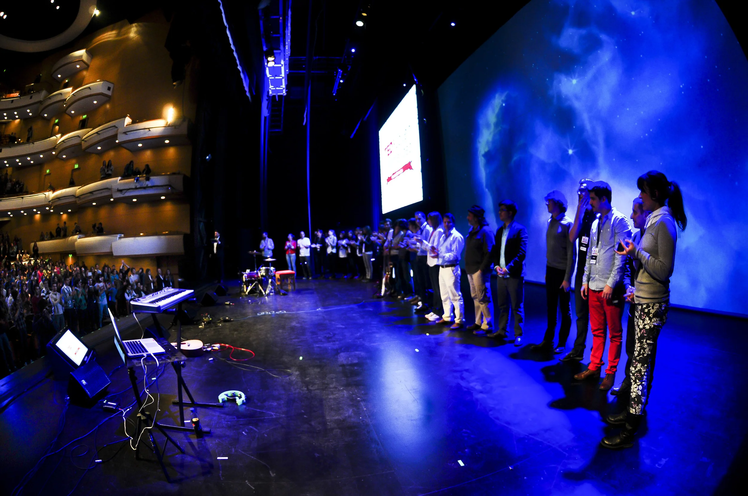 TEDx Montevideo participants standing across the stage for the final greeting.