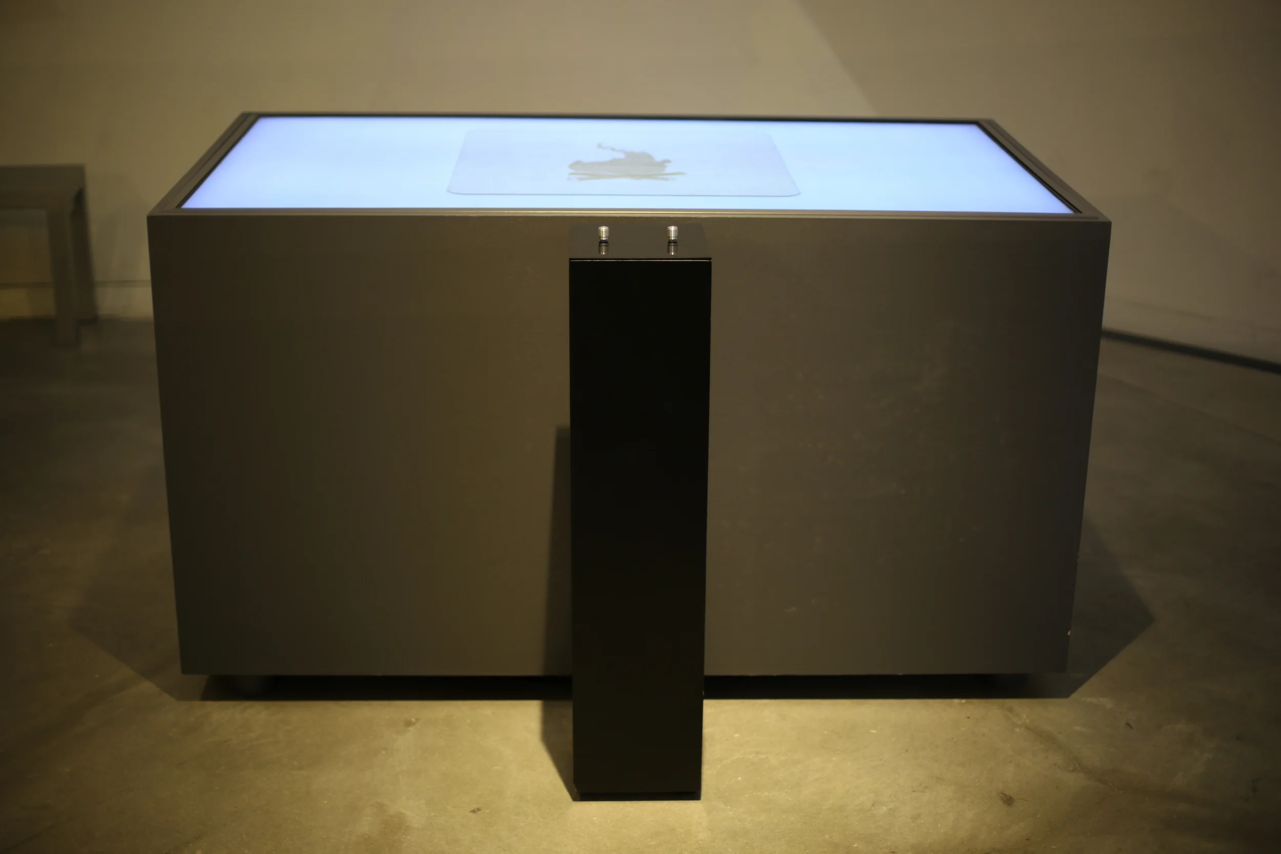 Two Systems: front view of the illuminated table and its black control pedestal.