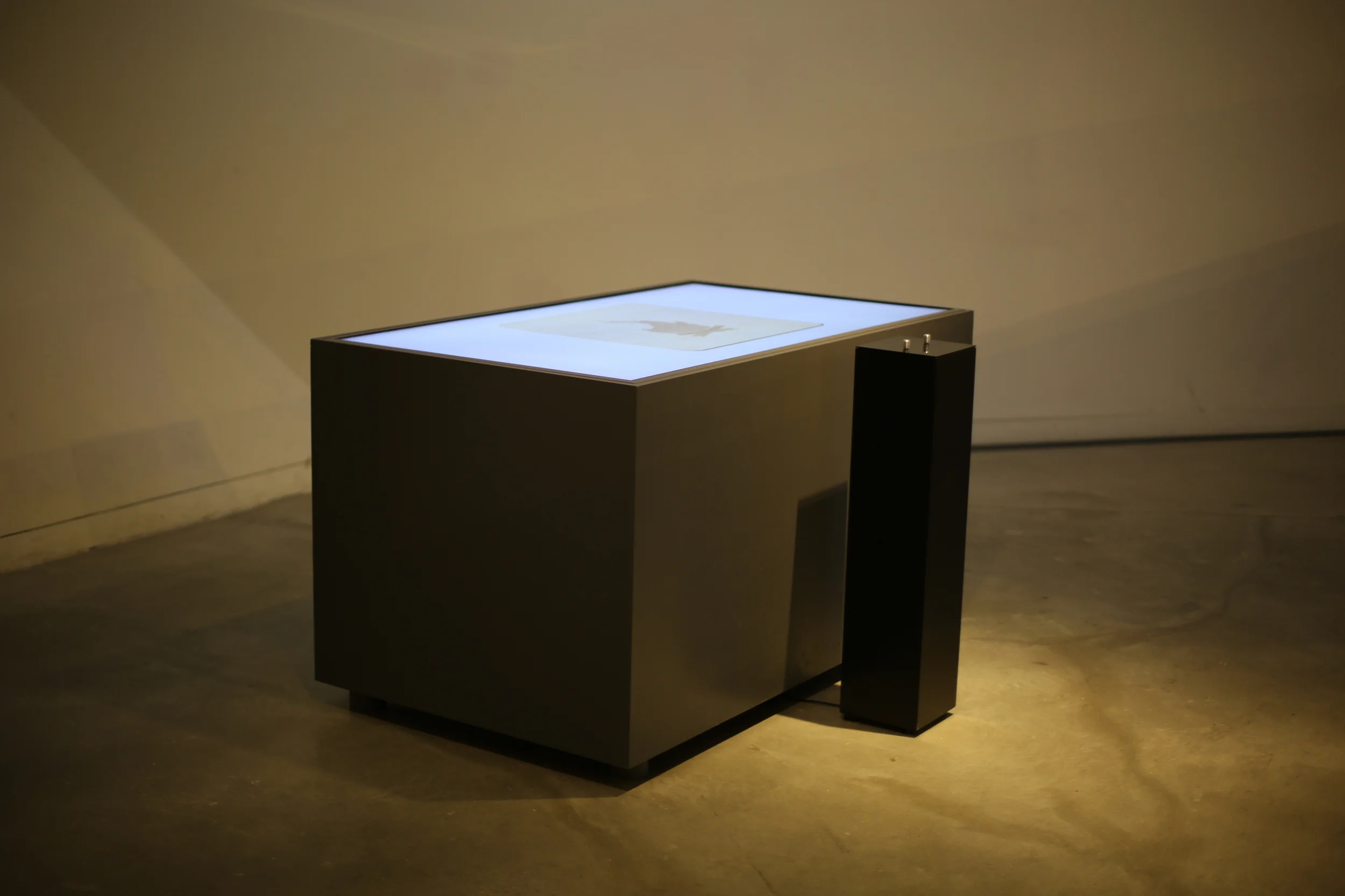 The illuminated table and control pedestal seen from an angle.