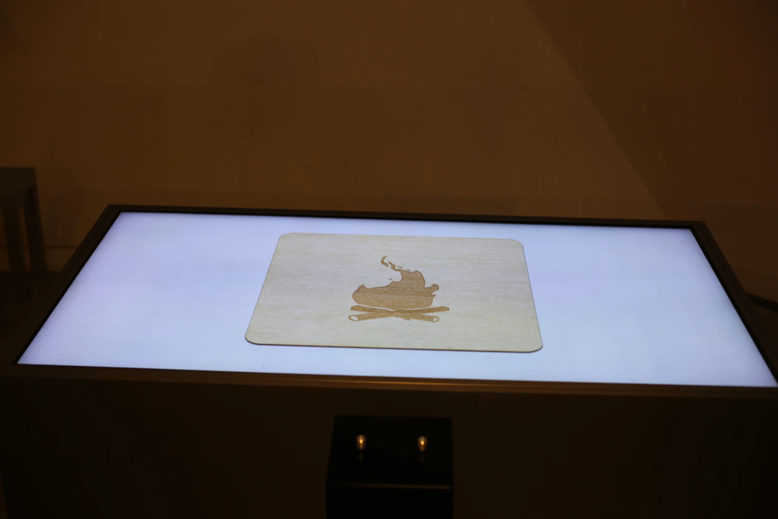 Close-up of an illustrated parchment shape on the illuminated tabletop.