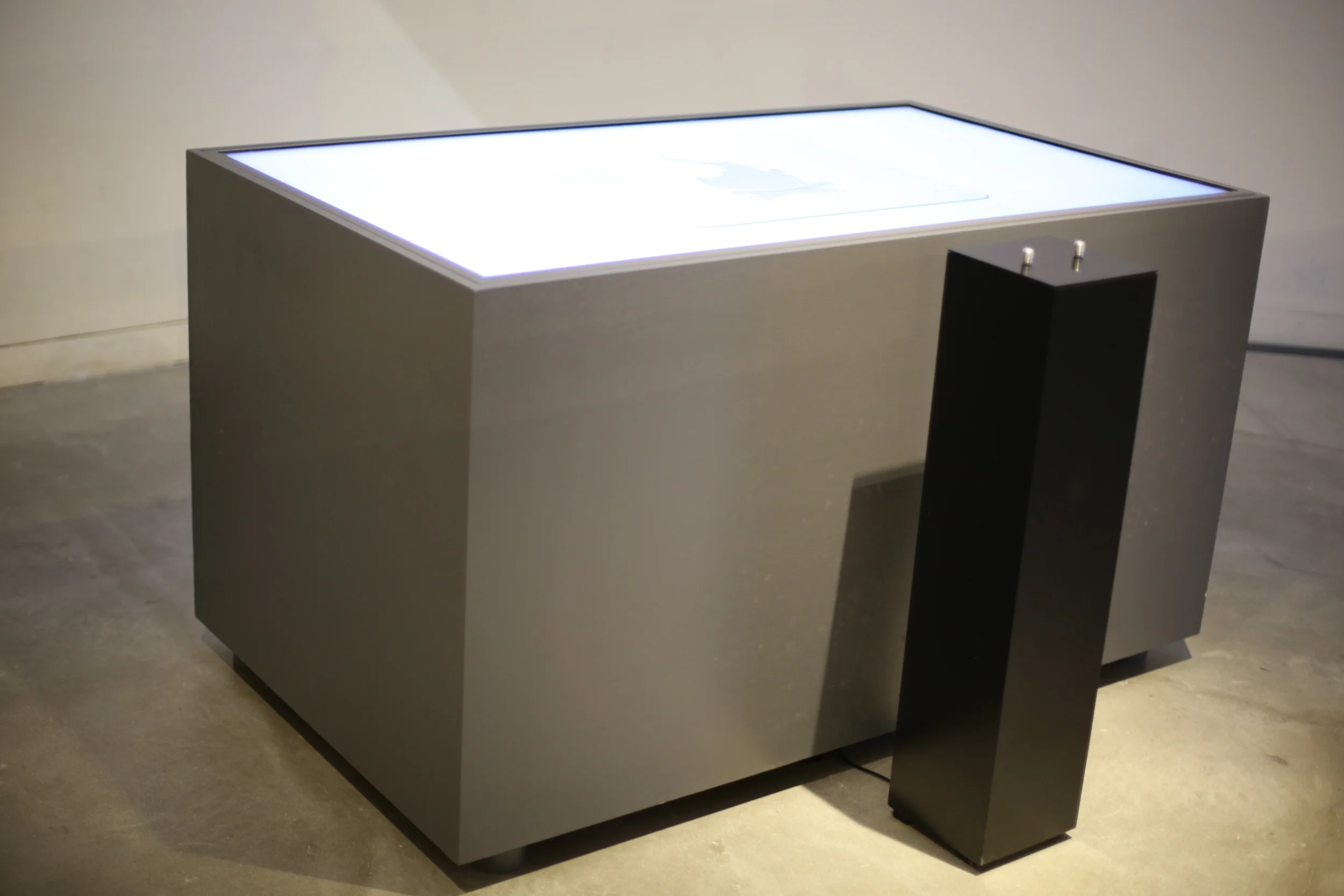 An angled gallery view of the illuminated table and its separate pedestal.