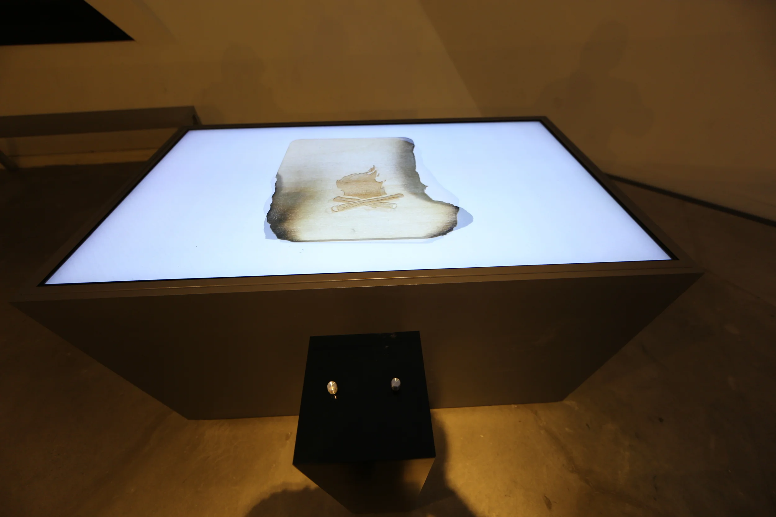 A darkened parchment shape on the bright tabletop, seen from above the controls.