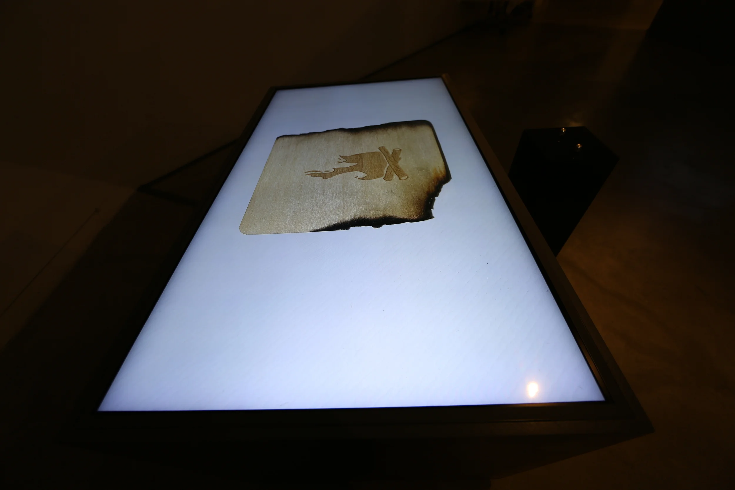A parchment shape with a darkened edge on the illuminated tabletop.
