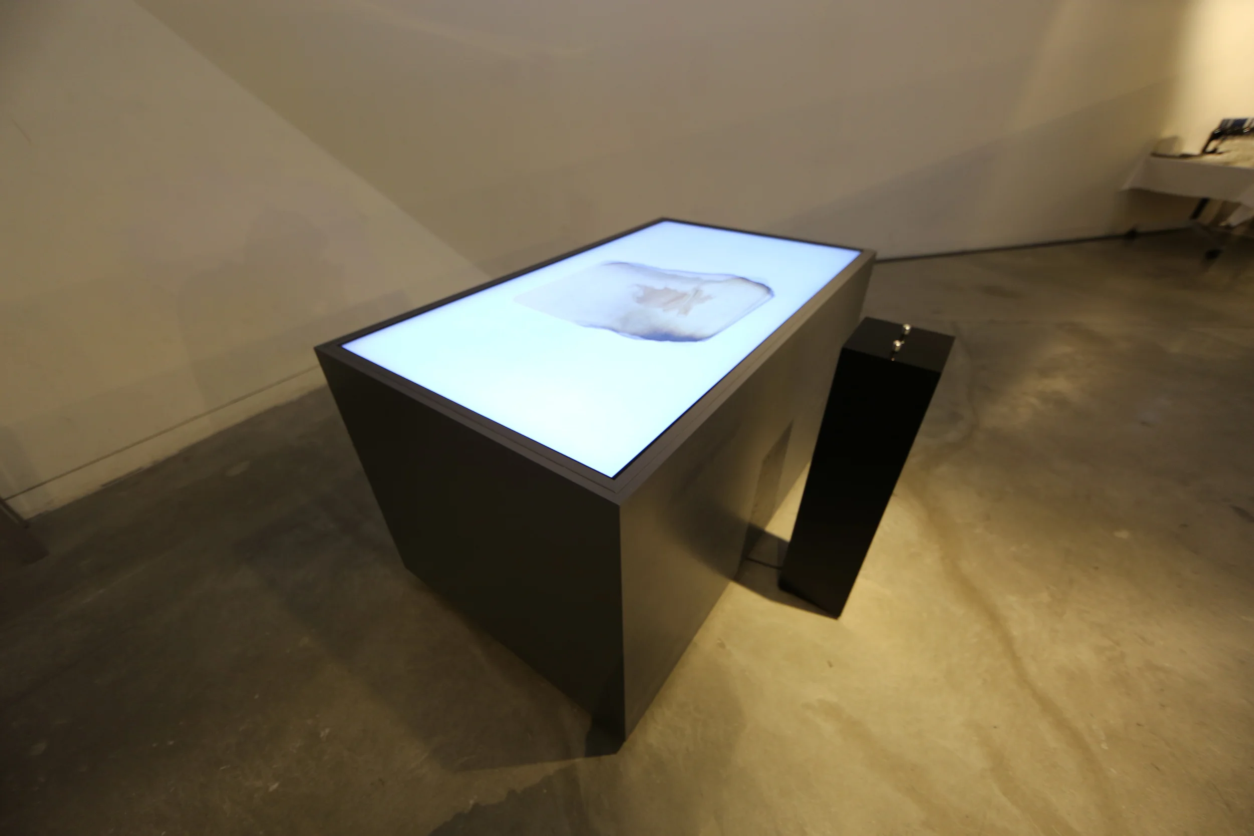 High-angle view of the illuminated tabletop and adjacent control pedestal.