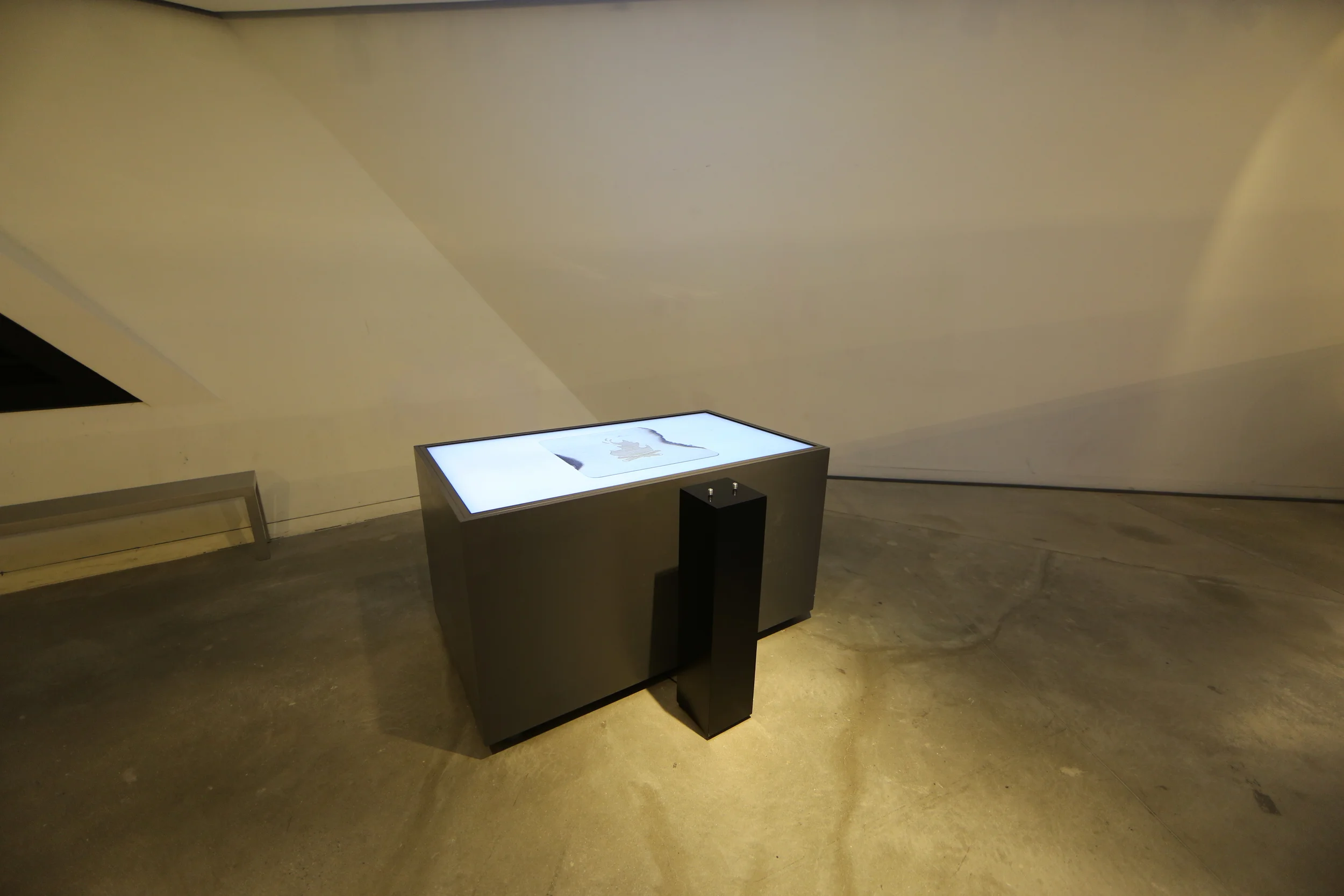 The illuminated table and pedestal in the open gallery space.